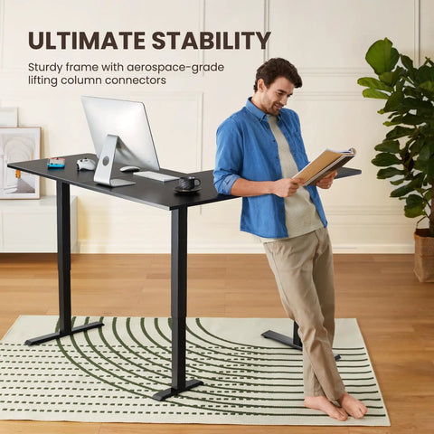 Man leaning on L Shaped Standing Desk 63 By 55 Inches Electric Sit Stand Table With Adjustable Height, black ergonomic computer desk