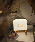 Toast Shaped Night Light With Cute Smile Face Double Or Single Side LED Toast Lamp on a stack of books