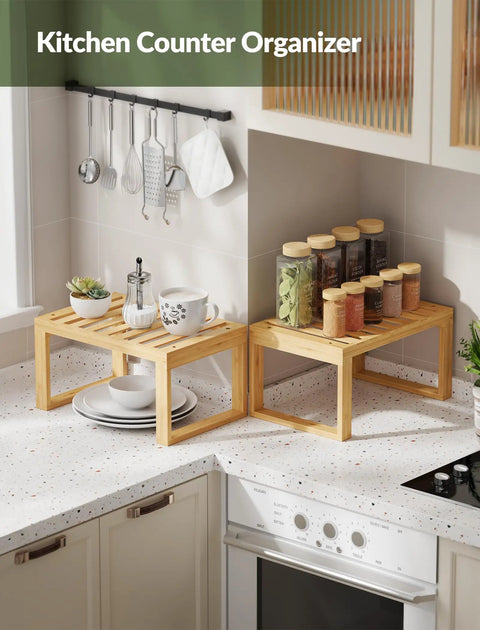 Heavy Duty Bamboo Cabinet Organizer Shelf Two Pack Stackable Kitchen Counter Rack Featuring Slatted Draining Surface To Air Out Dishes And Keep Counters Squeaky Clean with dishes and spice jars on countertops.