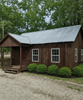 Ranchworn Aging Wood Stain Quick Turnaround Formula Dries In Half Hour on a wooden cabin with a metal roof, surrounded by greenery.