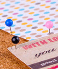 Kickass Bulk Supply Of 600 Heavy Duty Map Tack Push Pins Featuring Smooth Plastic Bead Heads And Vibrant Assorted Colors For Bulletin Boards And Classroom Organization with blue, pink, and black pins on corkboard