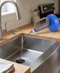 33 Foot Manual Drain Auger Snake Heavy Duty Spring Steel Pipe Cleaner positioned over a stainless steel sink ready for use.