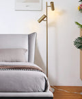 Cozy Elegant Modern Floor Lamp With Brass Finish, Tall Uplight Tree Style, beside bed in a bedroom, showing dual lighting heads.