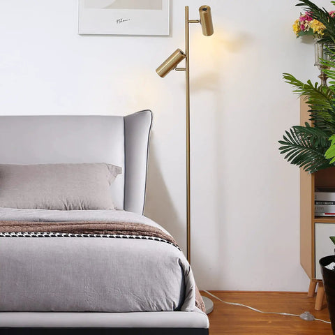 Cozy Elegant Modern Floor Lamp With Brass Finish, Tall Uplight Tree Style, beside bed in a bedroom, showing dual lighting heads.
