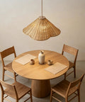 DLITISH 19'' Hand Woven Rattan Pendant Light with Glass Shade hanging above a round wooden dining table.