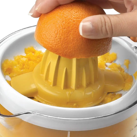 Hand pressing orange on Electric Citrus Juicer With 32 Ounce Pitcher No Fuss Pressure Activated Adjustable Pulp Control Self Reversing Reamer