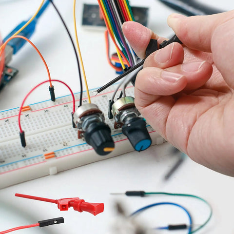 Person using 10 Piece Mini SMD IC Test Hook Clip Kit With Five Color Silicone Jumpers Wires for electrical testing on a circuit board.