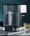Semi Automatic Espresso Maker With Built In Grinder And Milk Frother water reservoir and glass on table, sleek design.