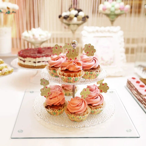 Cupcakes on a clear 2-tiered stand atop a Tempered Glass Cutting Boards Set For Kitchen Counters 2 Pack 16x12 And 12x8 Inches