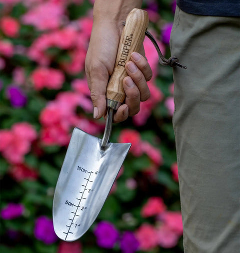 Person holding 13 Inch Stainless Steel Garden Trowel With Oak Handle And Leather Wrist Strap Built To Last For Digging And Planting