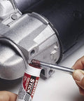Loctite 37701 red high-strength threadlocker stick, 9 g, applied to metal threads near a motor housing.
