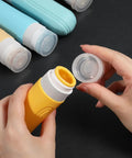Hands opening yellow bottle from On The Go Travel Bottles For Toiletries Set 5 Pack TSA Approved 3oz Leak Proof Refillable Containers