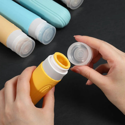 Hands opening yellow bottle from On The Go Travel Bottles For Toiletries Set 5 Pack TSA Approved 3oz Leak Proof Refillable Containers