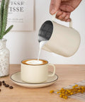 12 Oz Milk Frothing Pitcher With Clear Scale 304 Stainless Steel Barista Pouring Cup in use, frothing milk into a cappuccino.