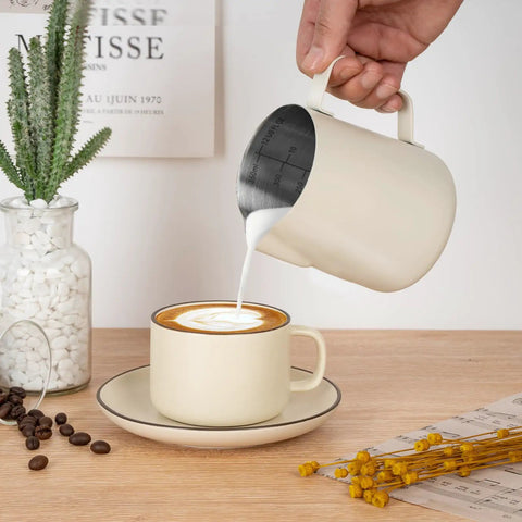 12 Oz Milk Frothing Pitcher With Clear Scale 304 Stainless Steel Barista Pouring Cup in use, frothing milk into a cappuccino.