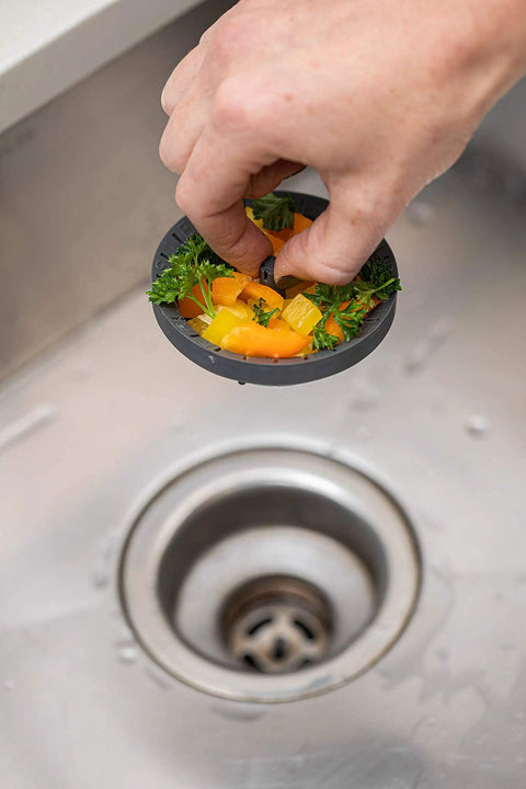 Hand holding 3.25 Inch Kitchen Sink Strainer Anti Clog Food Catcher With Flexible Drain Basket, capturing food above sink drain