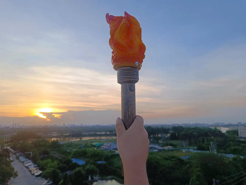Realistic Flameless LED Torch Light Prop Lamp For Parties, handheld style, against sunset in outdoor setting