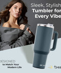 40 Oz Stainless Steel Tumbler With Handle And Straw For On The Go Hydration, Double Wall Vacuum Insulation Keeps Drinks Cold Or Hot Longer, Sweat Proof Easy Grip, BPA Free And Dishwasher Safe, Charcoal, displayed with woman in stylish coat.