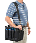 Man carrying a tool bag with blue tools, part of the Heavy Duty Four Drawer Rolling Utility Cart For Workshop Garage And Warehouse.