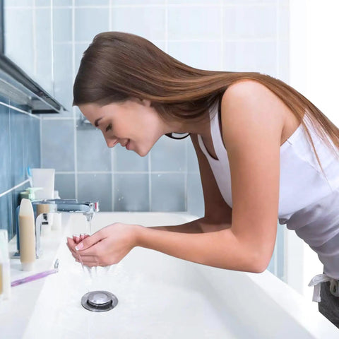 Woman washing hands in bathroom with Stainless Steel Bathroom Sink Stopper With Hair Catcher And Drain Strainer visible in sink.