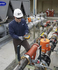 Technician using True-RMS Digital Multimeter Pro Grade Shop-Ready With 6000 Count Scale on industrial pipes outdoors.