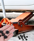 Hand holding Bulk 12 Pack Rubber Jack Oil Plugs in front of hydraulic jack under a vehicle