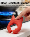 A hand holds red silicone utensil holder near stove, part of Red And Green Silicone Spoon Rests Set For Ladles, Tongs, Spatulas.