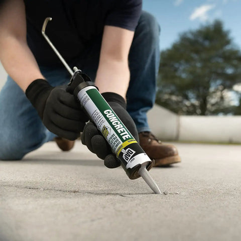 Person applying Concrete Watertight Filler And Sealant 10.1 Ounce Gray Pack Of 2 All Weather Waterproof Sealant on a driveway