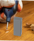 Gloved hand using DIY Floor Repair Kit For Cracked Tiles And Surfaces With Wax Block, Quick Heat Technology on wooden floor