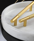 Gold knurled cabinet handles on a white marble plate