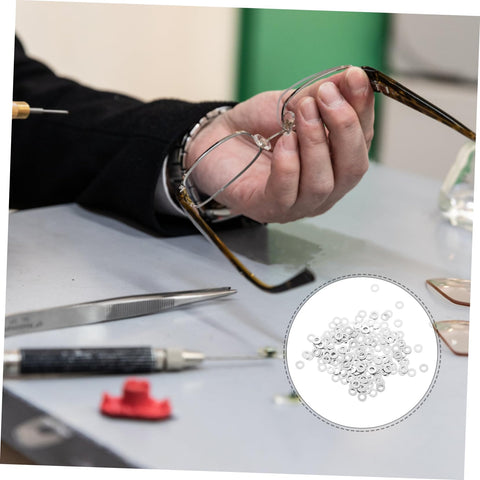 Man holding eyeglass frame, eyeglass frame gaskets and metal flat washers must have kit with 200 pcs replacement screws for rimless glasses quick repair and durable maintenance for long lasting eyewear life, tools on table.