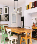 Dining room with Three Light Black Pendant Light With Seeded Glass Shades hanging over wooden table, eclectic chairs, and artwork.