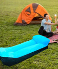 Inflatable Lounger Camping Couch For Adults And Kids, Air Sofa Chair in blue, set on grass near a tent and a picnic setup.
