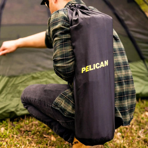 Person carrying a packed Self Inflating Sleeping Pad With Pillow And Arm Rest For Camping Waterproof Foldable Lightweight Air Mattress