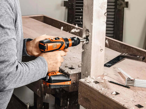 Battle Ready Heavy Duty Cordless Drill Driver Featuring Four Speed Rugged Metal Gearbox Brushless Motor Maximum Torque Output For Wood Metal Plastic Projects drilling into wood workbench.