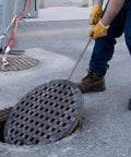 Worker using Stainless Steel T Hook Well Cover Hook For Manholes Pro Grade Heavy Duty Lift Tool to lift a manhole cover