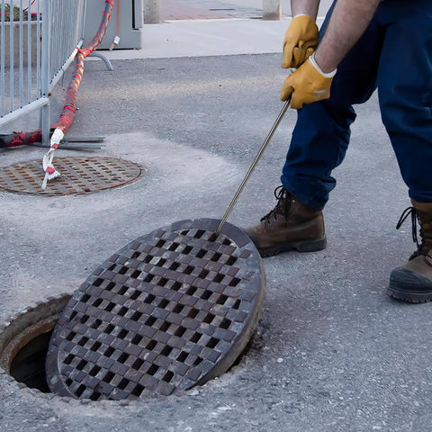 Worker using Stainless Steel T Hook Well Cover Hook For Manholes Pro Grade Heavy Duty Lift Tool to lift a manhole cover