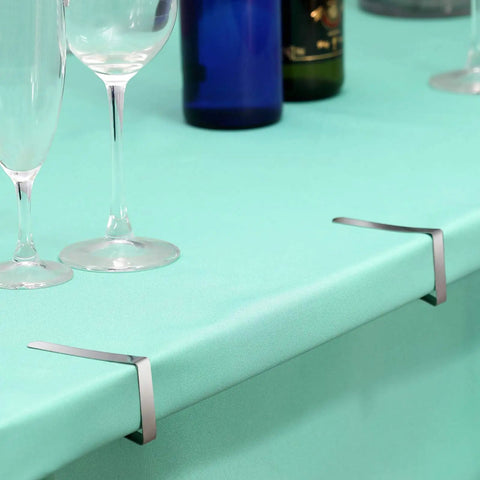 Heavy Duty Tablecloth Clips 12 Pack Stainless Steel Table Clip Clamps for Restaurants, Picnics, Marquees shown on green table.