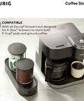 K Cup Pod And Ground Coffee Storage Organizer With Airtight Glass Canisters Holds 12 Oz Ground Coffee And 12 K Cup Pods Black Modern Kitchen Countertop Storage next to black coffee machine on white counter.