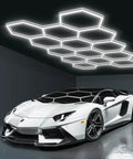 Hexagon LED Garage Lights For Home And Shop, Ultra Bright Honeycomb Panels, 456W High Power, 54720 Lumens, 6500K Daylight, 14 Grid System For Car Detailing, Warehouse, Basement And Gym illuminating a garage with a white sports car underneath.