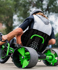 Child riding Green Machine 20 Inch Drift Trike For Kids 8 And Up with Dual Stick Steering, green and black, on sidewalk.