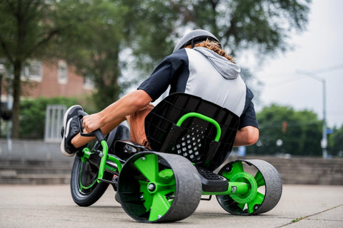 Child riding Green Machine 20 Inch Drift Trike For Kids 8 And Up with Dual Stick Steering, green and black, on sidewalk.