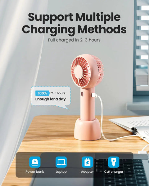 Mini Portable Handheld Fan With Base 3 Speed USB Rechargeable Dual Use Desk And Personal Fan Pink on wooden desk charging
