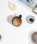 Self Heating Coffee Mug With Rechargeable Battery And Digital Temperature Control Keeps Your Drinks Piping Hot All Day Long Sleek Led Display Makes Temp Swaps A Breeze While The Roomy 16 Oz Black Body Delivers Total Upgrade Vibes For Any Desk Setup. Black 16oz mug with coffee and cream swirls on a white background.