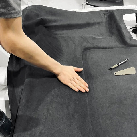 Auto headliner fabric suede with foam backing, black, 120 by 60 inches, laid flat with cutting tools