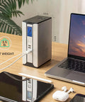 Compact 30000mAh Battery Backup Uninterruptible Power Supply With Surge Protector For Router, Modem, And PoE Devices, USB Type C And DC Ports, LiFePO4 Power Bank Keeps Your Internet On During Outages visible on desk next to laptop.