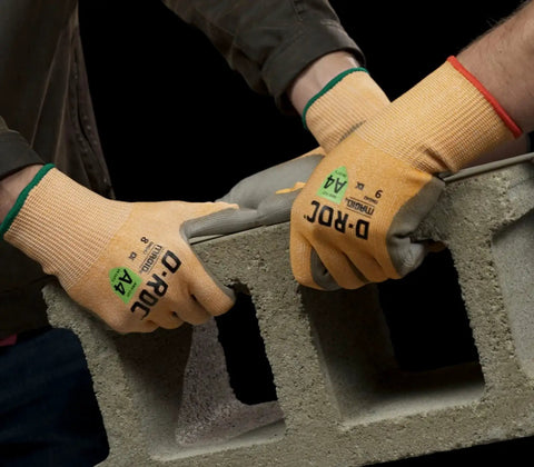 Two hands wearing DX Technology Cut Resistant Work Glove With Polyurethane Palm ANSI A4 Protection Size 9 gripping concrete block.
