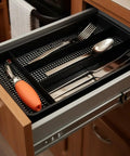 Swanky Four Compartment Utensil And Cutlery Drawer Organizer Tray In Matte Black For Kitchens Or Junk Drawers With Drainage Mesh Bottom keeps utensils neatly organized in a wooden drawer.