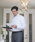 Man reading a document under decorative chandelier lit by Flicker Free Dimmable B11 LED Bulb With EyeComfort Technology.