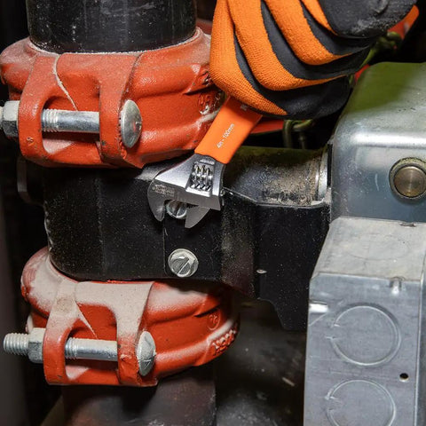 Extra Capacity Jaw 4 Inch Adjustable Wrench For Tight Spaces With Forged Heat Treated Alloy Steel SAE And Metric Scales Smooth Turning Knurl Dope Grip For Easy Single Hand Operation Plastic Dipped Handle Laser Markings Klein Tools O5064 in use on a pipe fitting.